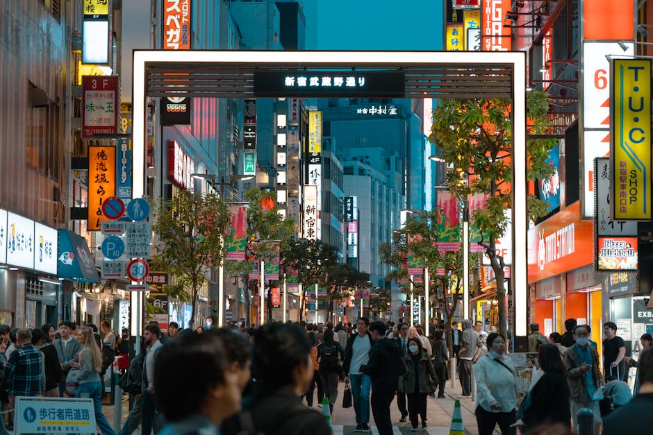 Vibrant Tokyo street scene in Shinjuku district, showcasing lively nightlife with crowds and neon signs.