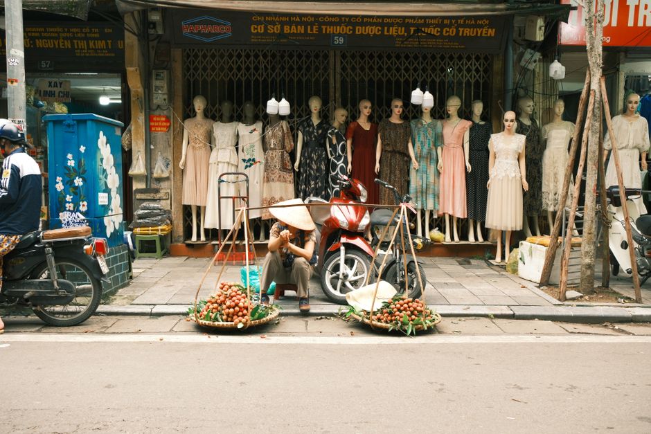 A street vendor sells fruit in front of a clothing shop in Jakarta, Indonesia.