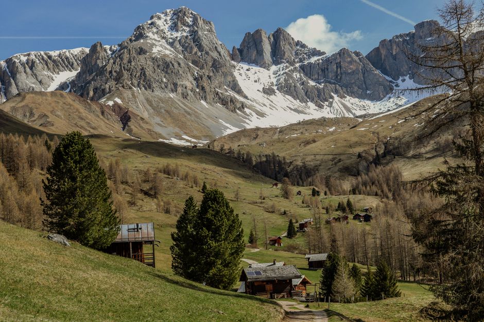 Majestic snow-capped mountains with rustic cabins in a serene valley.