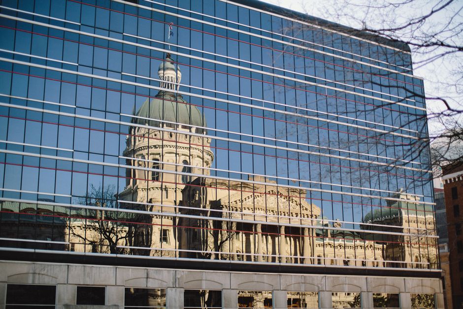 Reflection of a historic domed building on a modern glass facade, showcasing urban architecture.