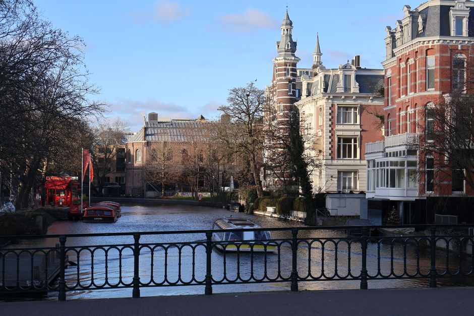 A picturesque Amsterdam canal framed by historic buildings and boats on a sunny day.