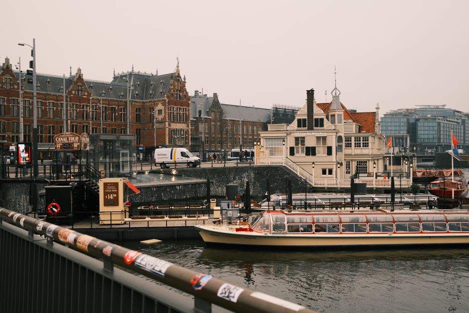 Capture of Amsterdam canal featuring tour boats and historic architecture, ideal for travel imagery.