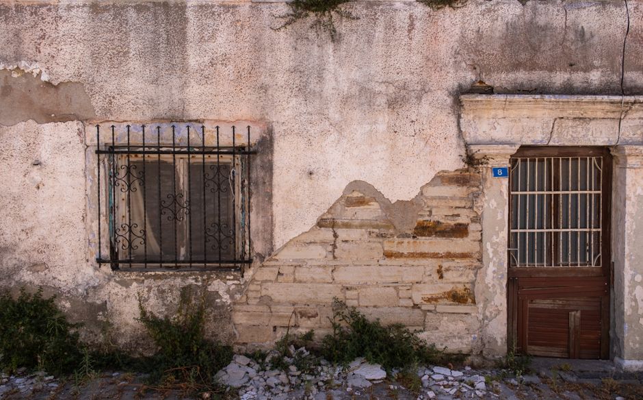 Rustic architecture of a weathered wall and door in Foça, İzmir, Türkiye.