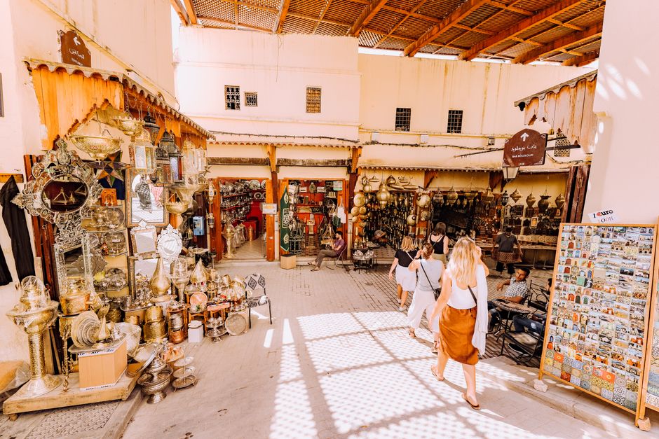 Lively market scene in a traditional Middle Eastern bazaar with tourists exploring shops.
