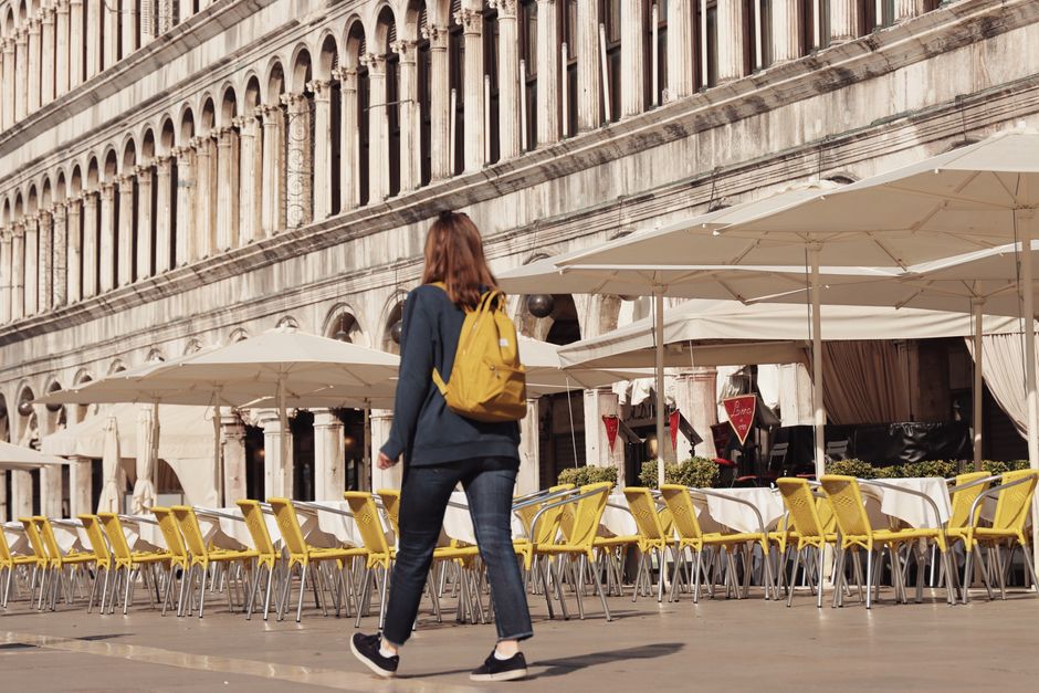 Young woman with a yellow backpack walking through Saint Mark's Square, Venice.