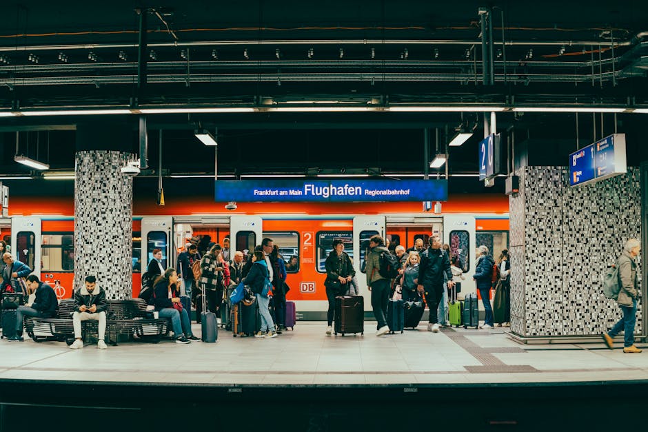Passengers wait on the platform at Frankfurt am Main Flughafen train station with a regional train in the background.