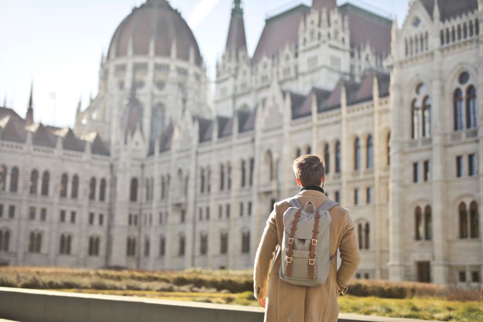 A tourist admires the grandeur of the Hungarian Parliament Building in Budapest during daylight.