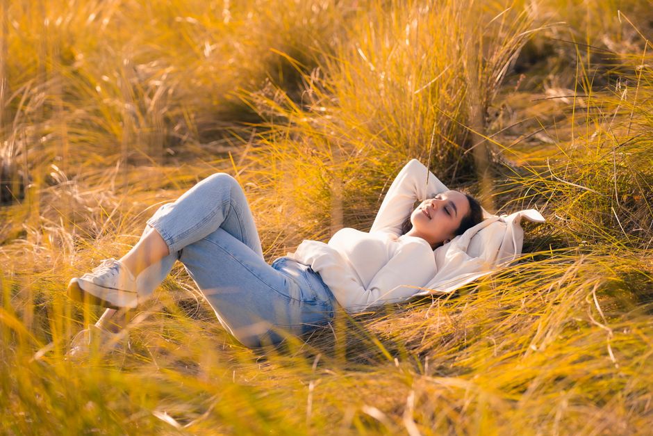 A woman enjoying a peaceful moment lying in a sunlit field of golden grass.