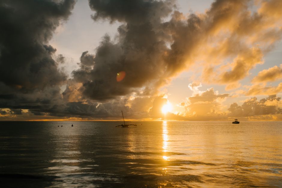 Breathtaking view of rippling sea with floating boats under cloudy sky at sunrise